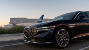 Genesis G90 front end with DRLs on parked in front of Boeing 787