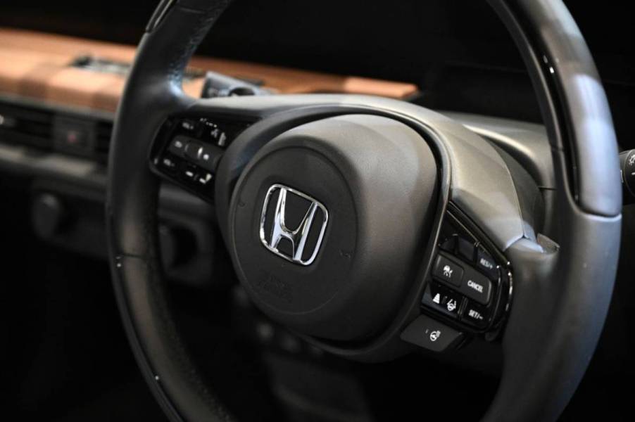 A closeup shot of a steering wheel in a Honda car.