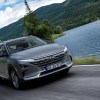 A gray Hyundai Nexo driving next to a lake by a mountain. The Hyundai Nexo hydrogen fuel cell complicates fueling.