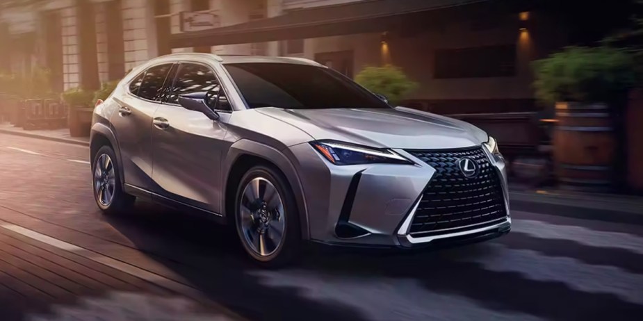 A gray 2023 Lexus UX luxury subcompact hybrid SUV is driving on the road. 