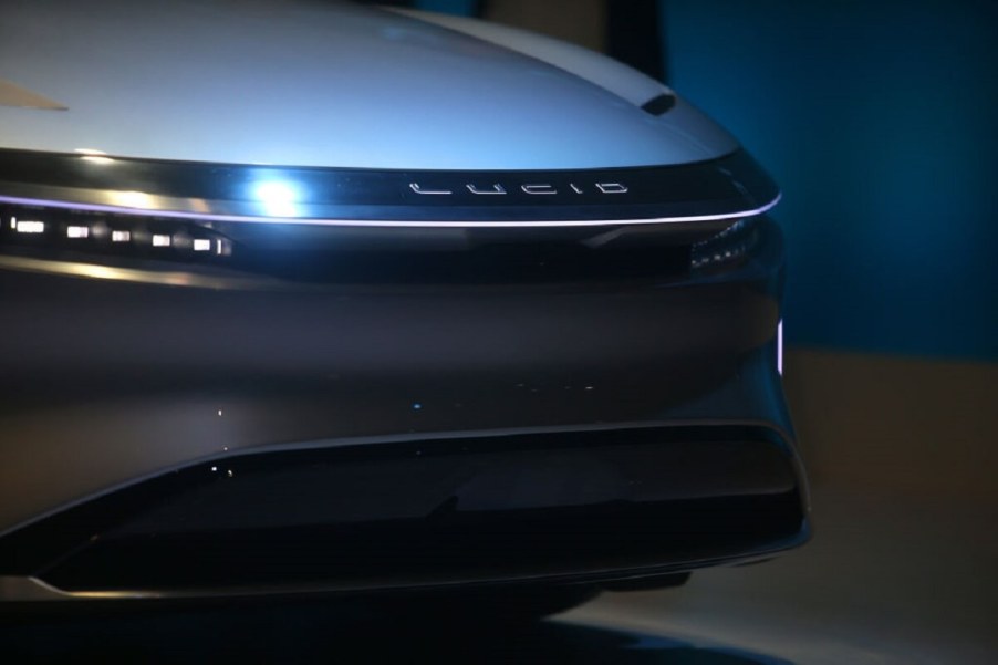 A Lucid Motors Air EV shows off its front-end styling on a stage at an auto show.