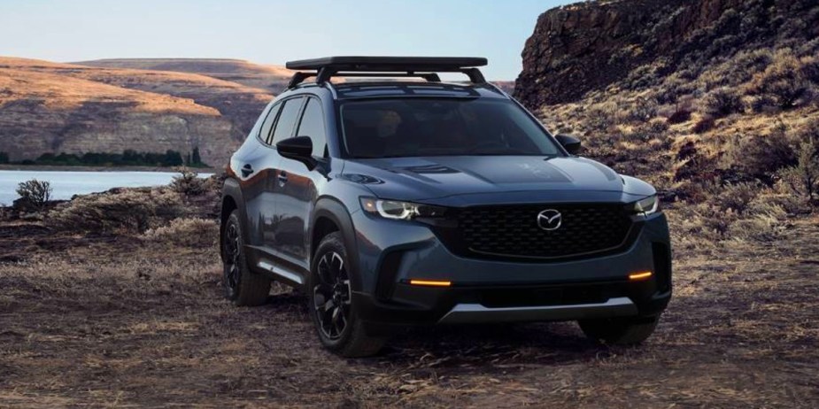 A blue Mazda CX-50 small SUV is parked off-road. 