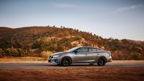 Gray Nissan Maxima driving on a desert road. Nissan Maxima trims offer a bunch of variety for car shoppers