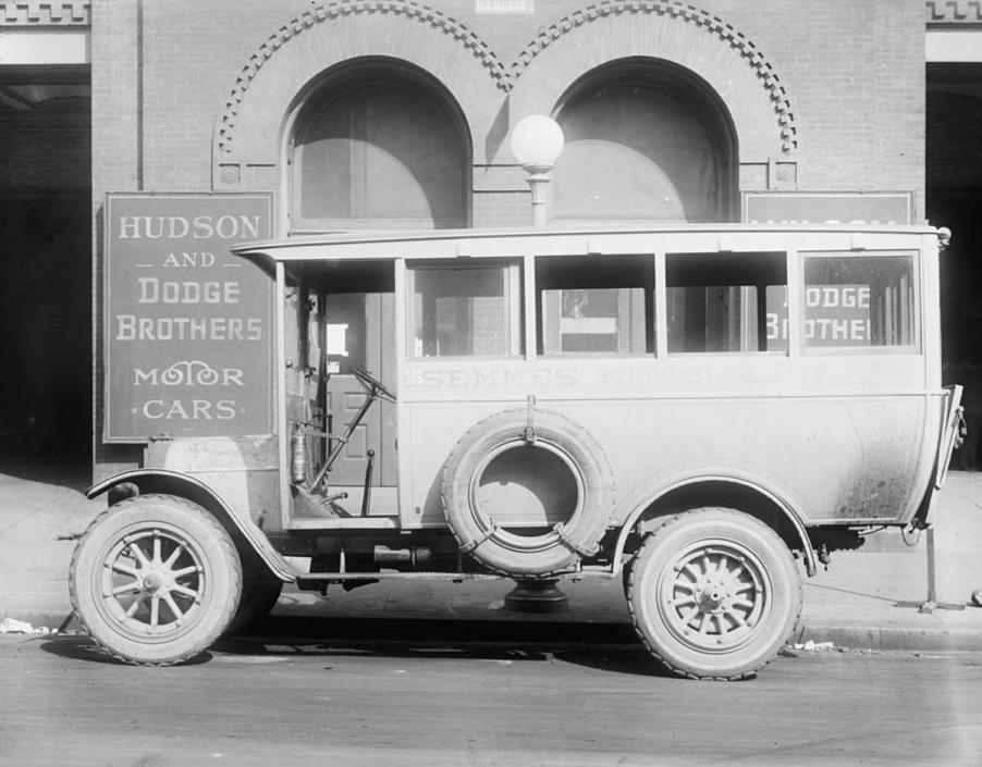 A black and white photo of an old Dodge car outside the factory.