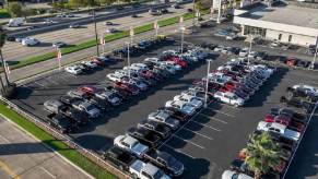 A lot of used RAM 1500 trucks, GMC Sierra 1500s, and other vehicles sit under the sun.