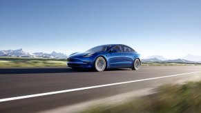 A blue 2022 Tesla Model 3 Long Range stretches its legs on a long country road.