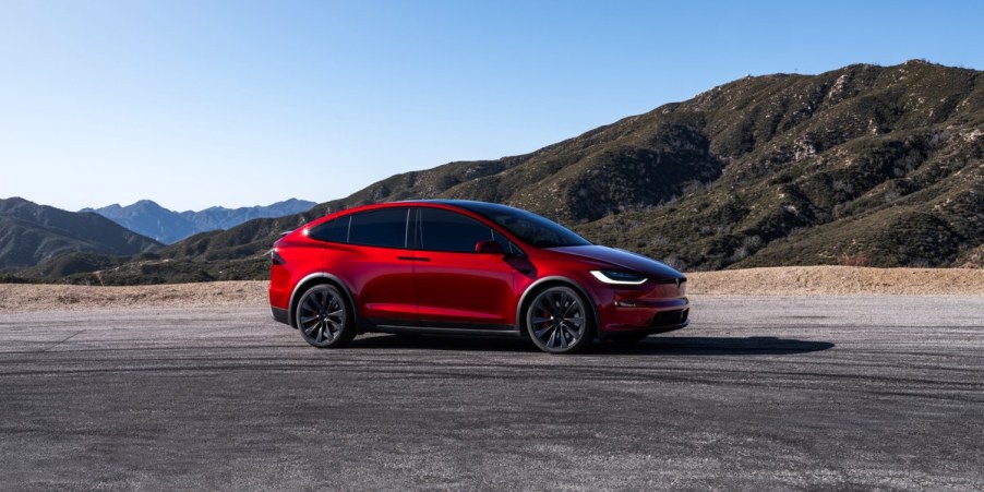 A red Tesla Model X midsize SUV is parked.