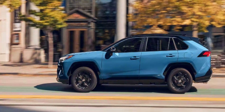 A blue 2023 Toyota RAV4 Hybrid small SUV is driving on the road.