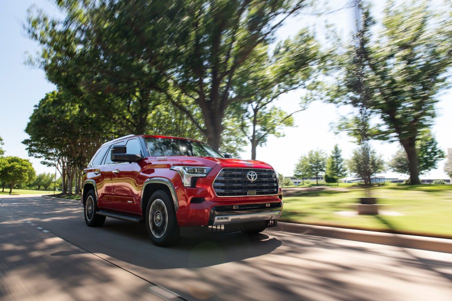 A red 2023 Toyota Sequoia driving down a shaded road on a sunny day. This Toyota SUV is gaining in popularity