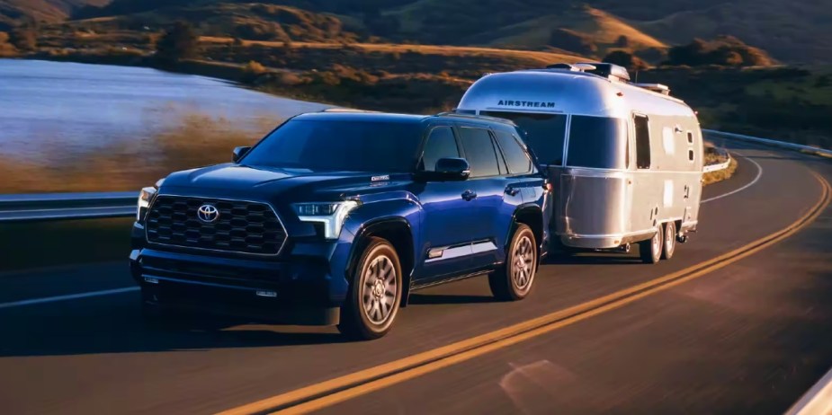 A blue 2024 Toyota Sequoia full-size SUV is towing a trailer. 