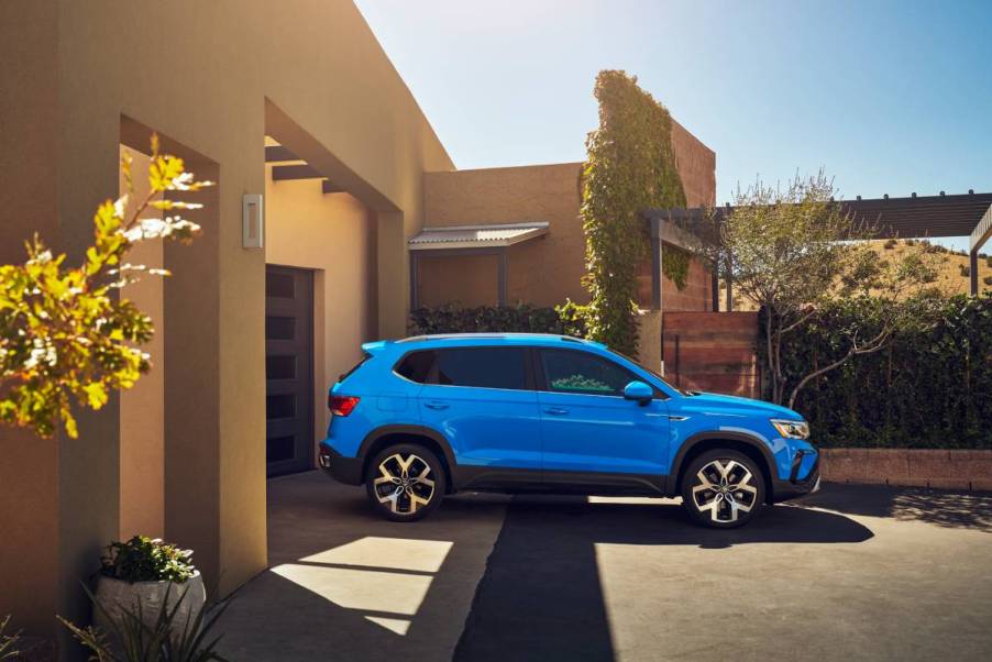 A blue Volkswagen Taos on parked outside a house.