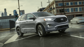 A 2024 Ford Edge midsize SUV driving through an overcast city crosswalk