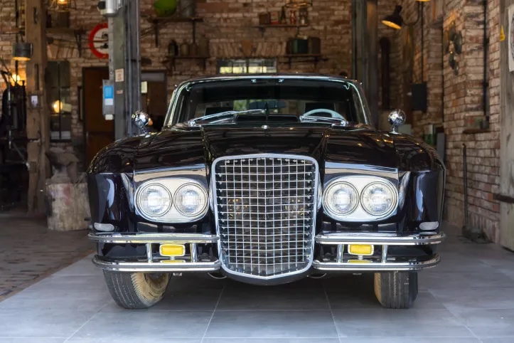 The grille and four front headlights of a Gaylord Gladiator car parked in a garage, brick visible in the background.