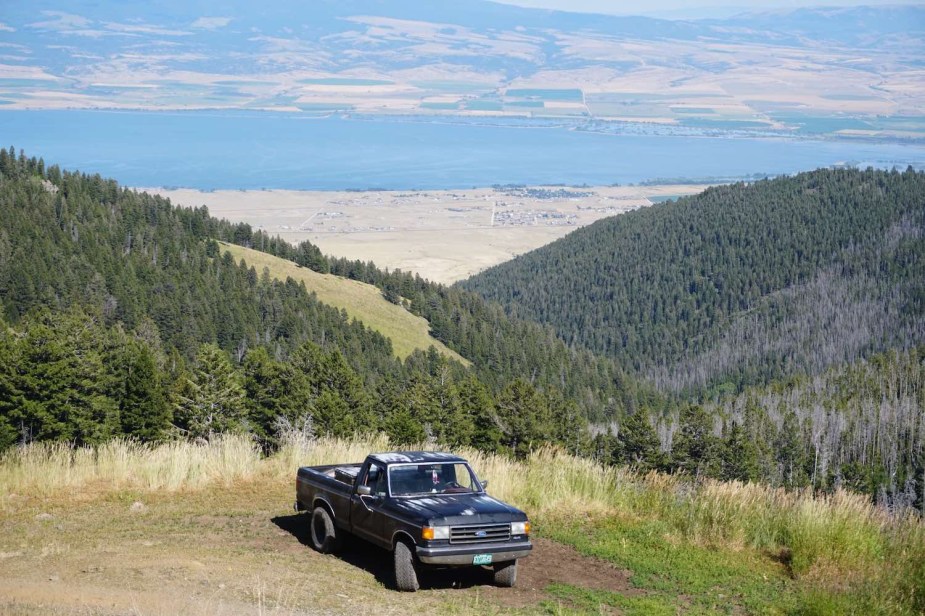 4WD truck on a mountaintop during an overlanding camping trip, a lake visible in the background.