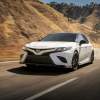 A white 2020 Toyota Camry travels on a mountain highway