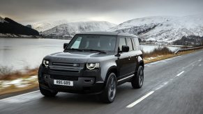 A dark-gray 2022 Land Rover Defender 110 V8 drives through a country road.