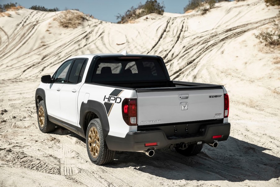 The rear of a white Honda Ridgeline on a dirt hill. The Ridgeline and Santa Cruz are competitors in the compact truck space.