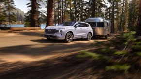 A white 2023 Hyundai Santa Fe midsize SUV is driving off-road.