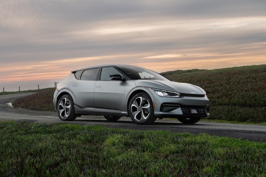 The 2023 Kia EV6 in silver driving on a winding road at dawn. Kia EV6 owners have a few things they love about this vehicle