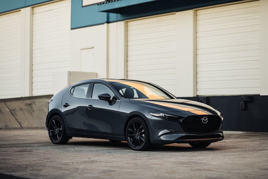 A black 2023 Mazda MAzda3 Hatchback front 3/4 shot at sunset in an industrial complex