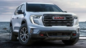 A white 2024 GMC Acadia midsize three-row SUV is parked outdoors.