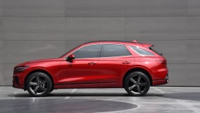 A red 2024 Genesis GV70 side view against a gray backdrop. 2024 Genesis GV70 trims come in only two configurations.