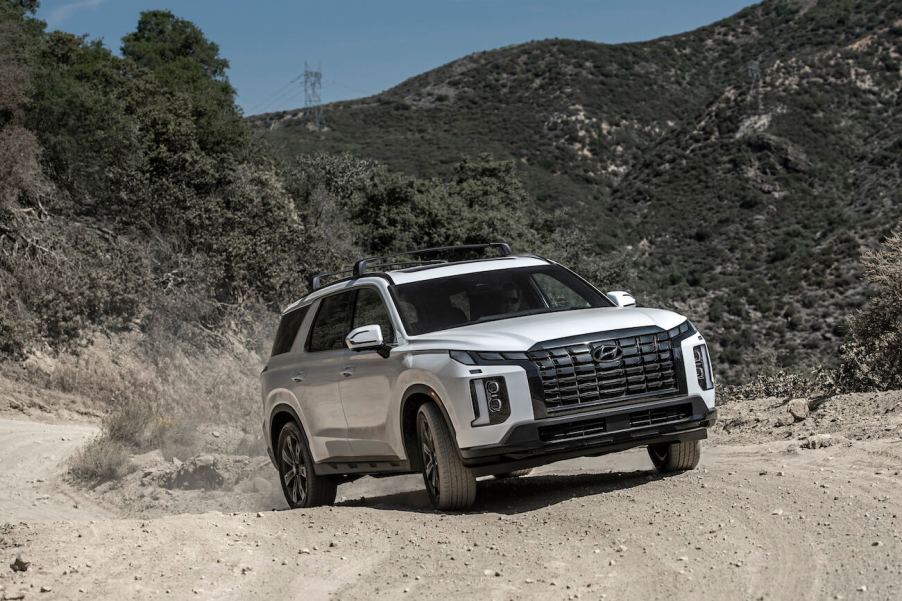 A white 2024 Hyundai Palisade on a dusty trail in the mountains. Hyundai Palisade owners love lots of parts of their vehicles.