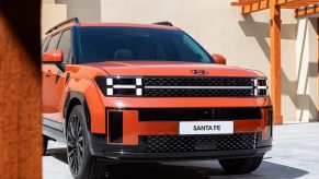 The front grille of an orange 2024 Hyundai Santa Fe. Price is a major consideration for drivers interested in the three-row SUV.