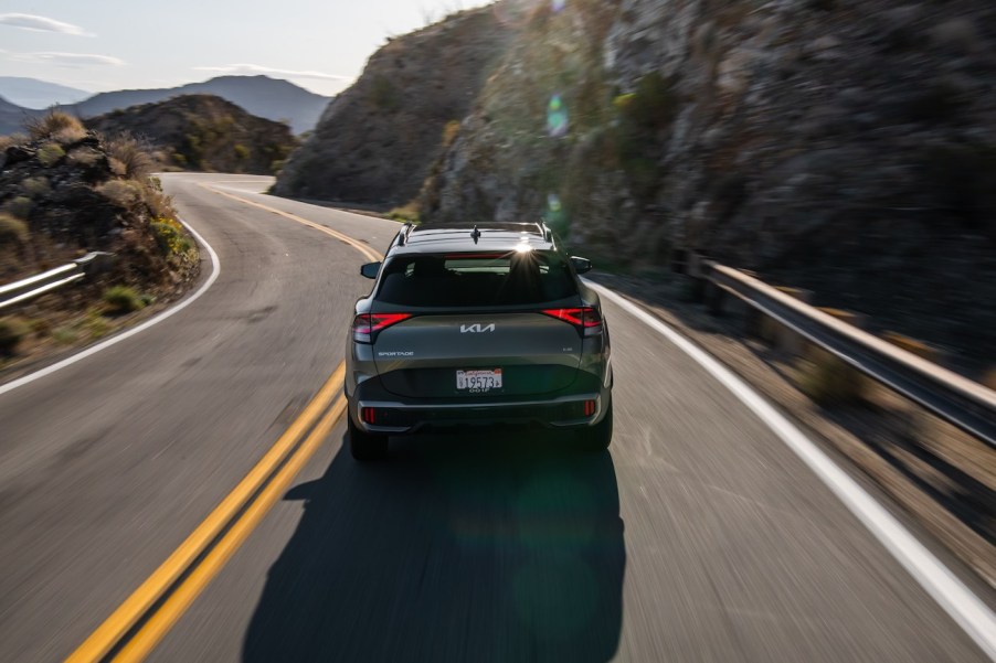 The rear of a gray 2024 Kia Sportage driving a long a winding road. The 2024 Kia Sportage's price is a big positive point for the SUV.