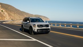 2024 Kia Telluride in gray driving along the coast. The 2024 Kia Telluride price makes it a good option over some luxury competitiors.