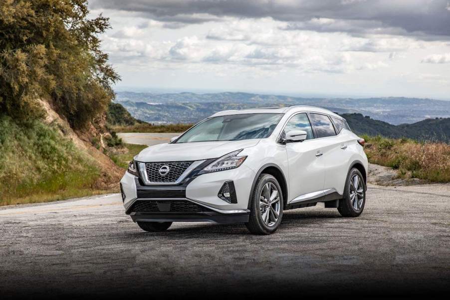 A white 2024 Nissan Murano midsize SUV parked on gravel overlooking mountains on a cloudy day