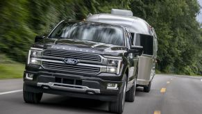 The 2024 Ford F-150 Hybrid pulling a camper on the road