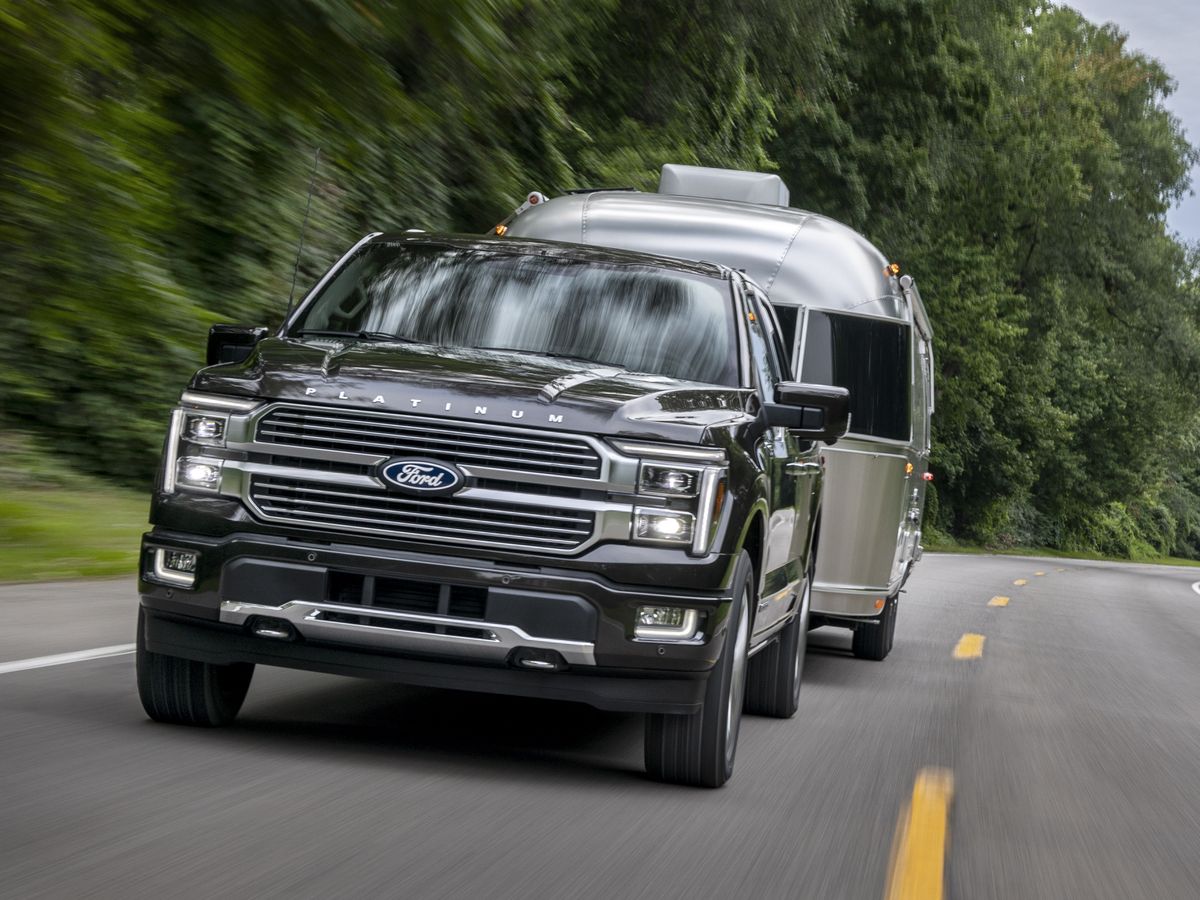 The 2024 Ford F-150 Hybrid pulling a camper on the road