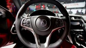 An Acura logo on a steering wheel. Acura is moving away from hybrid models.