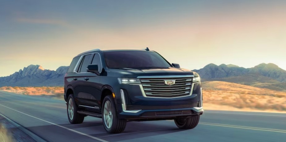 A black 2023 Cadillac Escalade is driving on the road. 