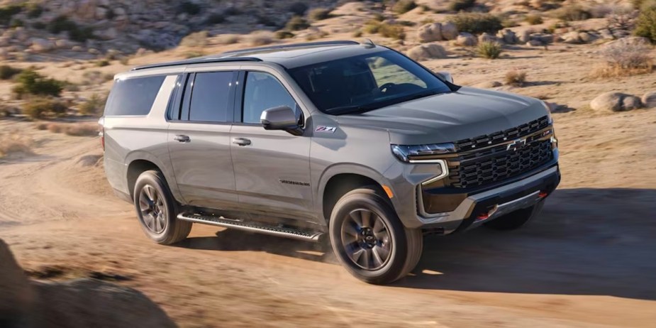 A gray 2023 Chevrolet Suburban full-size SUV is driving off-road. 