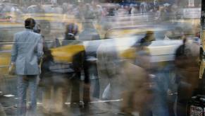 Pedestrians and yellow taxis passing through a busy city intersection.