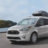 A silver Ford Transit Connect driving next to a lake. Ford Transit sales aren't doing too hot right now.