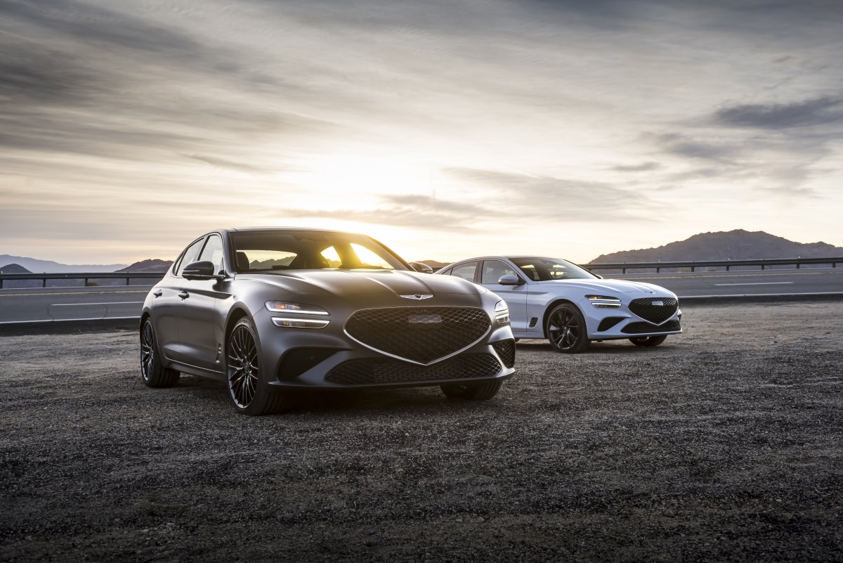 Two Genesis G70 luxury sedans parked at dusk