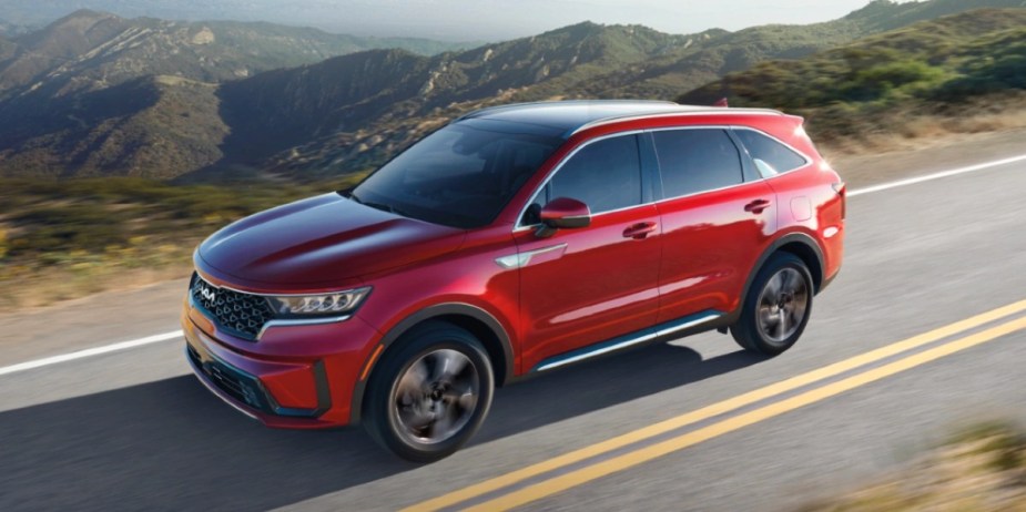 A red 2023 Kia Sorento Hybrid midsize hybrid SUV is driving. 