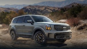 A gray 2024 Kia Telluride midsize three-row SUV is driving off-road.