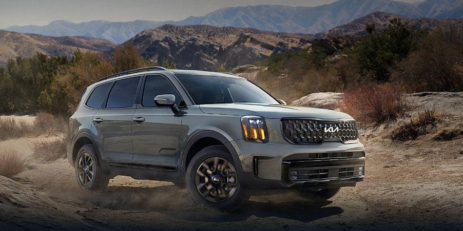 A gray 2024 Kia Telluride midsize three-row SUV is driving off-road.