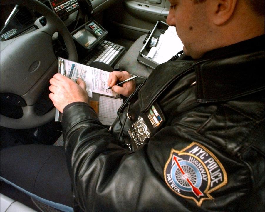 A New York police officer writes a ticket for speeding.