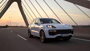 A Porsche Cayenne Turbo e-Hybrid PHEV midsize luxury SUV driving across a bridge