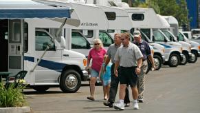 People walking around looking at RVs at a dealership.