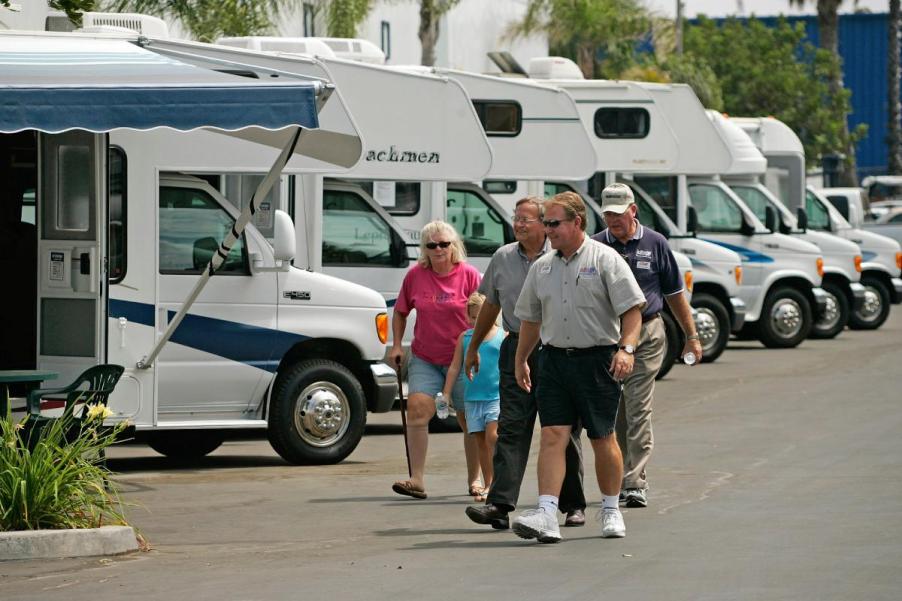 People walking around looking at RVs at a dealership.