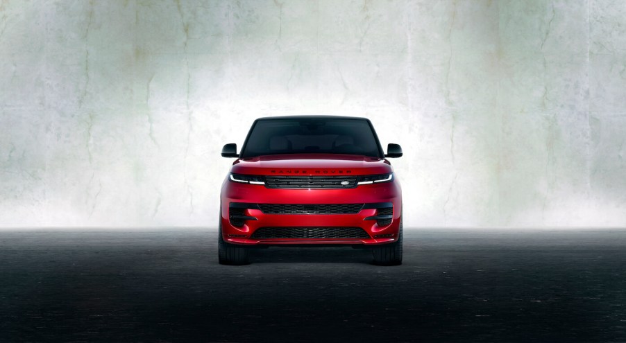 A red Land Rover Range Rover Sport on display against a gray backdrop. The Range Rover Sport's price is high, but it does add value.