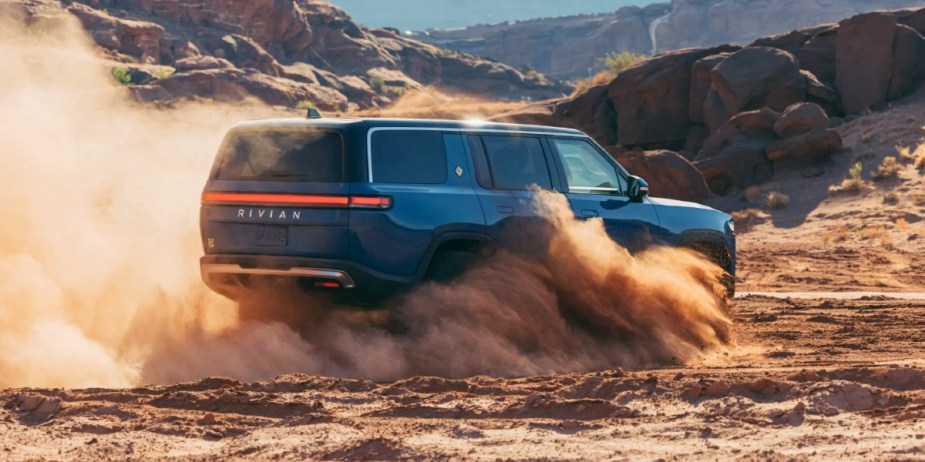 A blue Rivian R1S electric SUV is driving off-road. 