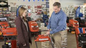 A salesman pitching a lawn mower model to a potential customer inside a Briggs & Stratton Simplicity store section