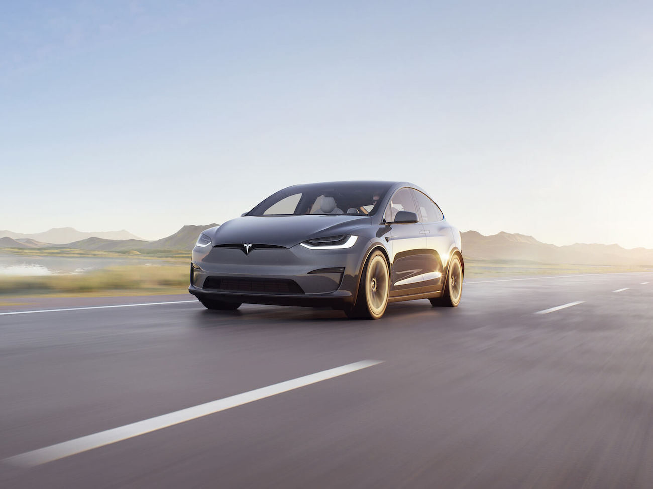 Gray Tesla Model X driving down a road. Tesla advertising is nonexistent.